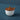 Be Home Amelia Pinch Pot, a white ceramic cellar with a teak lid and teak spoon, on a dark blue background