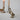Pewter duck candle snuffer in antique gold standing beside taper candles