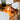 Lit filament lightbulb lying on a wooden dinner table between white plates and glasses