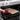 Hand in red pot holder sliding a tray of cookies out of a stainless steel oven