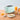 Mint green Smeg toaster on a wooden table with orange juice, sandwich and toast triangles