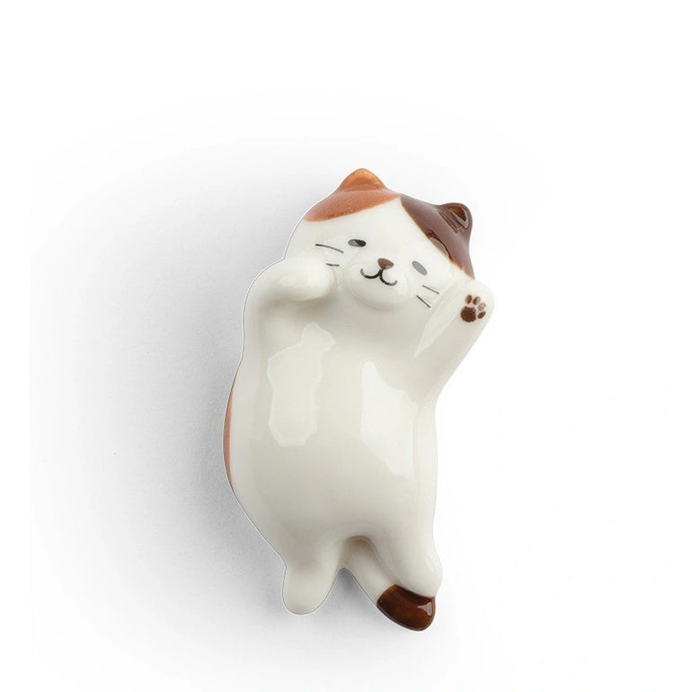 Ceramic calico cat chopstick rest lying on its back with paws raised