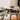 Dining table setting with dark green bowls and glasses on a wooden table, with a cushioned chair in the background.
