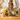 Two bee-themed crochet coasters on a wooden surface with a floral-patterned towel in the background.