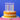 Pastel twirl candles lit on a layer cake against a blue background