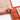 Close-up of the Paprika Red pot holder pocket opening, hanging loop and ampersand label
