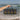 Hand holding a striped bag on a beach with ocean waves in the background