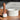 White marble mortar with a wood-handled pestle on a wooden table