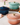 Three colorful cast iron cookware pots on a light surface with a vase of flowers in the background.