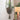 Macrame plant hanger with a plant against a neutral wall.