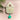 Cuckoo clock with a green pendulum on a pink background