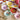 Colorful ceramic flower-shaped dishes on a floral-patterned cloth with pink flowers.
