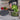 Person transferring lettuce into a clear container with a black lid on a kitchen counter.