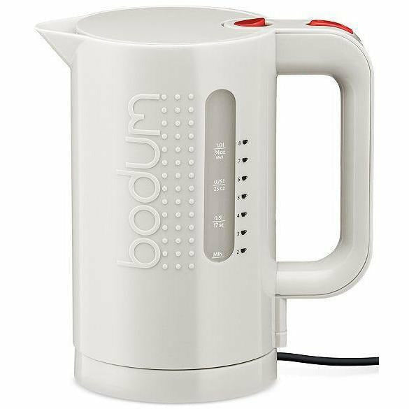 Bodum Bistro electric kettle with a stainless steel body, black handle, and lid, boiling water on a kitchen countertop.