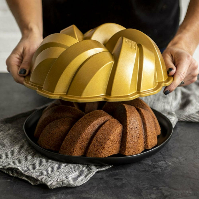 Lifting the gold Braided Bundt pan off a baked cake
