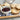 Floral and star stamped sandwich cookies filled with red jam beside a bowl of jam
