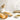 A perforated Italian loaf pan with a non-stick coating, two freshly baked loafs of bread, a small white bowl with sauce, a garlic clove, and a decorative white vase with a sprig of dill on a white surface.