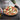 Pizza baked on a charcoal Emile Henry pizza stone held with oven mitts
